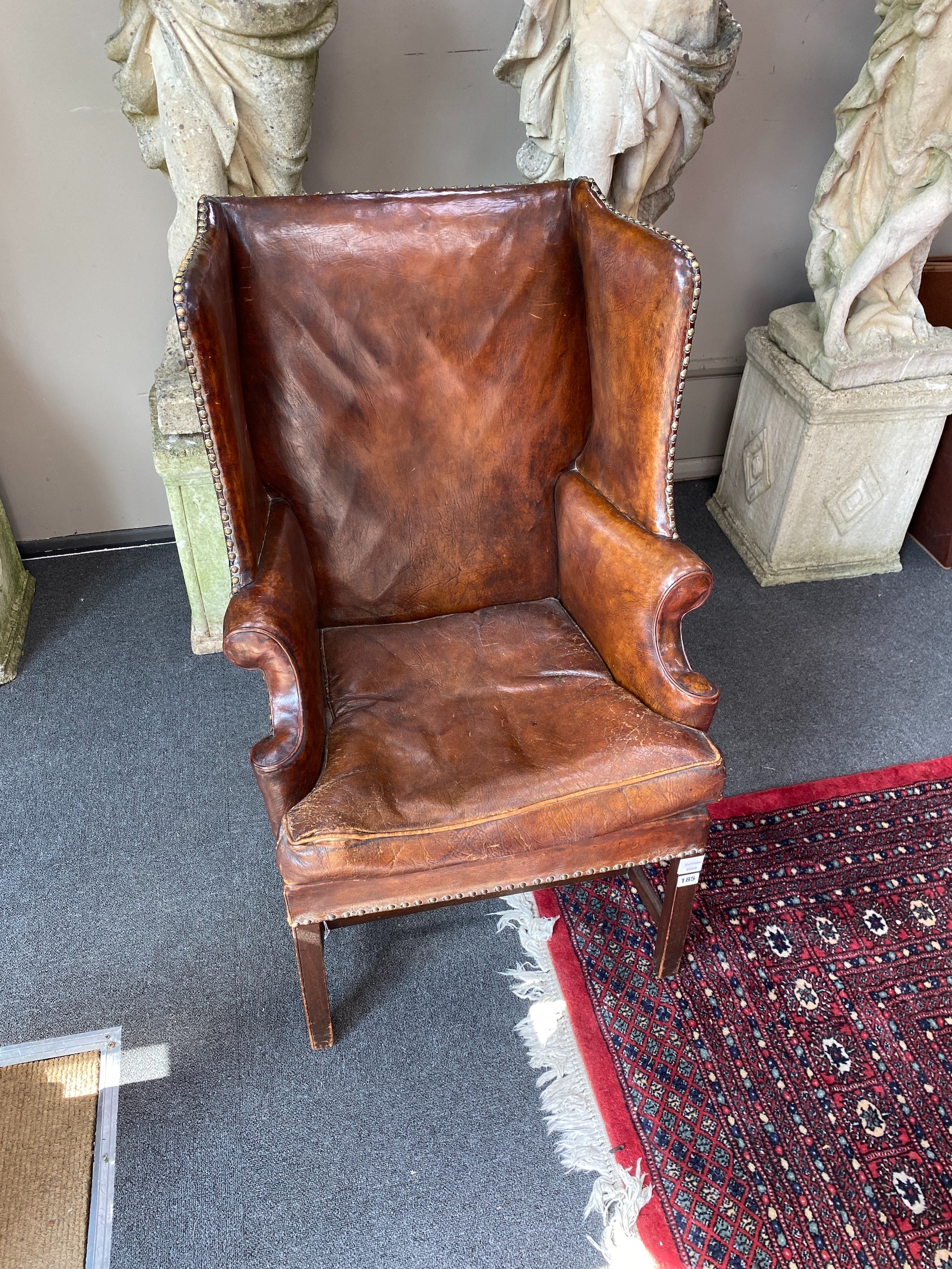A George III style mahogany brown leather upholstered wing armchair, width 64cm, depth 60cm, height 101cm